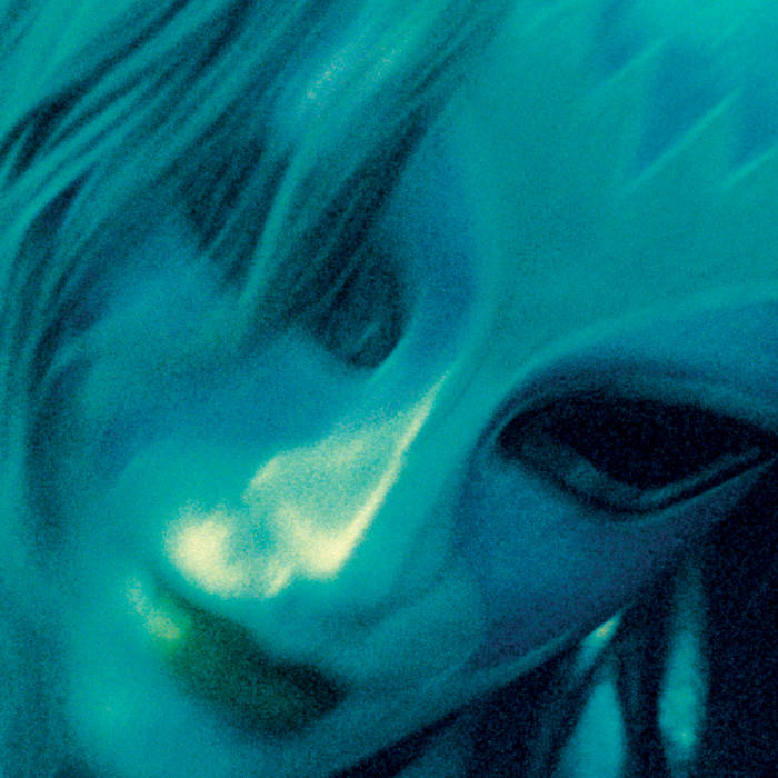 image is a blurry closeup of a painted face mask with hair falling over one eye