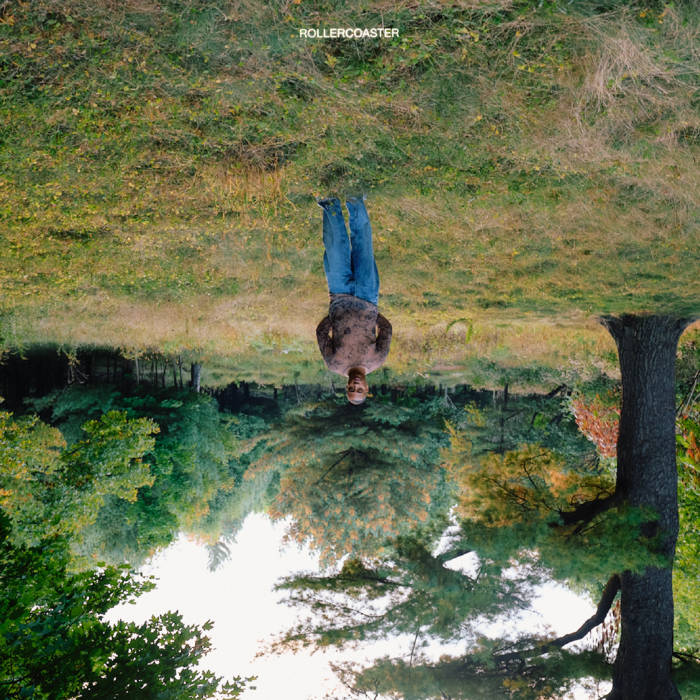image is an inverted photograph showing a man standing in the clearing of a forest